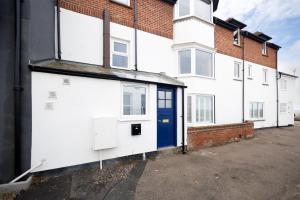 a row of white houses with a blue door at The Wave - 3 bed beach front home in Sheringham in Sheringham