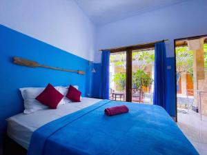 a blue bedroom with a large bed with red pillows at Pandan Wangi in Nusa Lembongan