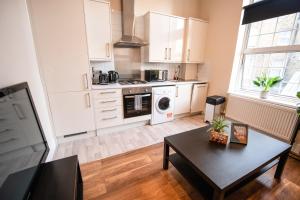 a kitchen with white cabinets and a table in a room at Charming 2-Bedroom flat in Shepherd's Bush in London