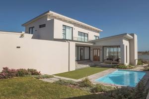 a white house with a swimming pool in front of it at Coastal Retreat, wine and relax in Hermanus