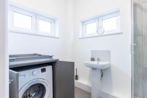 a laundry room with a washing machine and a sink at The Eldern - Spacious, Netflix, free Parking, close to A1 in Peterborough