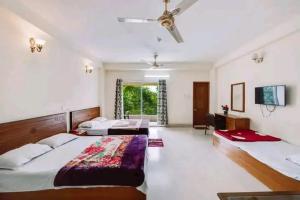 a large bedroom with two beds and a tv at Hill Crown Hotel & Resort in Bāndarban