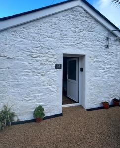 a white building with a door and some plants at Heart of Falmouth - Entire Studio Apartment in Falmouth