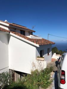 a white house with a car parked next to it at La Campana de Arriba in La Guancha