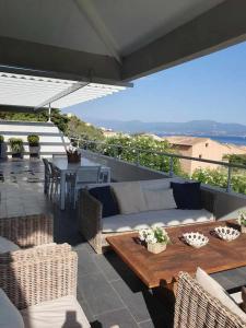 a patio with a couch and a table and chairs at VILLA GOLFE AJACCIO près des plages in Ajaccio