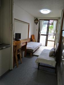 a room with two beds and a desk with a computer at Minshuku Zabaru in Ishigaki Island
