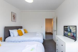 a bedroom with two beds and a flat screen tv at The Eldern - Spacious, Netflix, free Parking, close to A1 in Peterborough