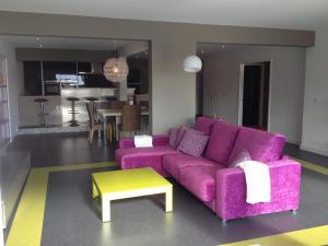 a living room with a purple couch and a table at VILLA GOLFE AJACCIO près des plages in Ajaccio