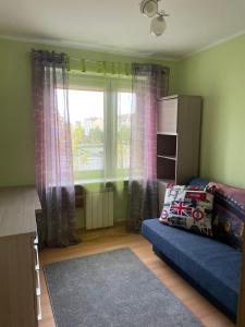 een woonkamer met een blauwe bank en een raam bij LUX APARTAMENT in Giżycko