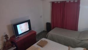 Habitación con 2 camas y tocador con TV. en Departamento La Argentina en San Luis