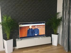 a flat screen tv in a living room with two men at Premium Apartaments-Chociszewskiego 6 c in Leszno