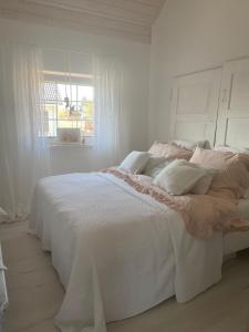 a white bed in a white bedroom with a window at Dom Anna in Pisz