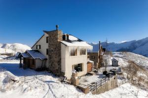 stary budynek na szczycie pokrytej śniegiem góry w obiekcie Snow Time Cottage w mieście Gudauri