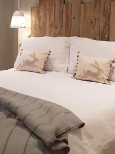 Una cama con sábanas blancas y almohadas. en Appleton House, en Thornbury