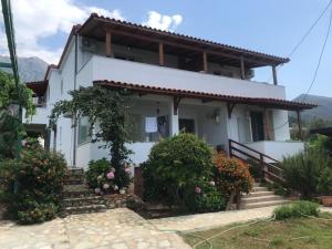 a white house with flowers in front of it at XHEKO ROOMS in Dhërmi