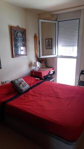 una camera con due letti rossi e una finestra di "Casa TOLIMA" a Barcellona