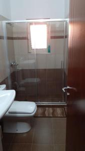 a bathroom with a shower with a toilet and a window at XHEKO ROOMS in Dhërmi