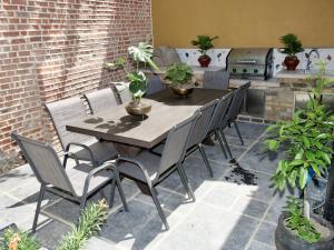 a wooden table and chairs on a patio with plants at Luxury 9 Bed Manor House Hot Tub Cinema Room SkyTV in Saffron Walden