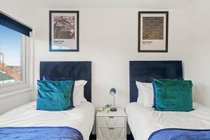 two beds with blue pillows in a bedroom at Boutique Penthouse in Yorkshire - Top Floor in Castleford