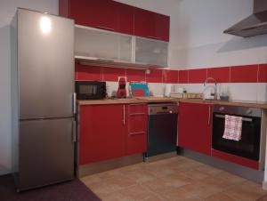 a kitchen with red cabinets and a stainless steel refrigerator at Apartmán Rezidence Čertovka 2121 free parking garage in Karlovy Vary