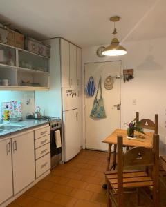 cocina con armarios blancos, mesa y nevera en Lindo y cómodo departamento en Pinamar - Otilia Residencias en Pinamar