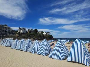 rząd niebiesko-białych parasoli w paski na plaży w obiekcie Le Moringa, à 2 min de la plage, Hyper Centre, vue mer de la fenêtre w mieście Dinard