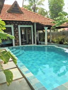 a swimming pool in front of a house at Marari Dreamz Homestay in Mararikulam