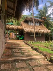 a house with a thatched roof and a pathway at Coconut Castle at La Lodge at Long Bay in Big Corn Island