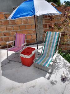 2 sillas de césped y una sombrilla en el patio en Refúgio sossego (casa de campo), en Camaçari