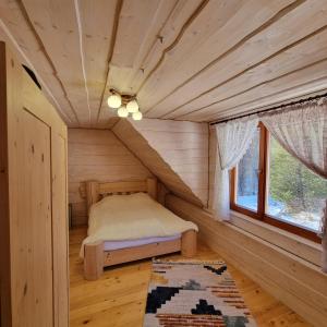 a bedroom in a log cabin with a bed and a window at Vysoka brama дерев'яний будиночок з чаном in Oriv