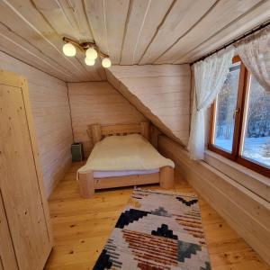 a small room with a bed in a wooden house at Vysoka brama дерев'яний будиночок з чаном in Oriv
