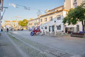 a cobblestone street in a town with a red cart at Casa da Avó Maria in Arraiolos
