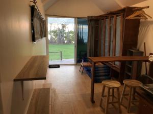 ein Wohnzimmer mit einem Tisch, Stühlen und einem Fenster in der Unterkunft Walden Koh Lanta - Tiny Homes by the Sea in Ko Lanta