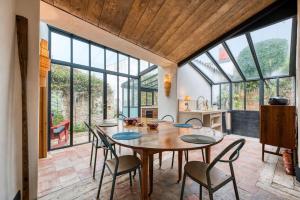 a dining room with a table and chairs and large windows at Le 9 bis, Idéal pour un couple. in Le Bois-Plage-en-Ré