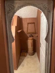 a bathroom with an archway with a toilet and a barrel at Ryad lcaid in Tissint