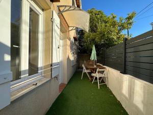 d'une terrasse avec de la pelouse verte, une table et des chaises. dans l'établissement Studio avec terrasse-Orange Vélodrome, à Marseille