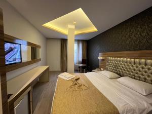 メルスィンにあるGrand Ezel Hotelの大型ベッドとテレビが備わるホテルルームです。