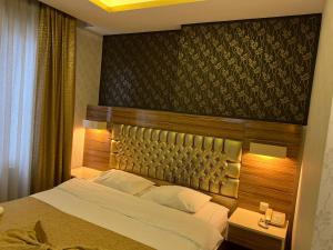 1 dormitorio con 1 cama grande y cabecero de madera en Grand Ezel Hotel, en Mersin