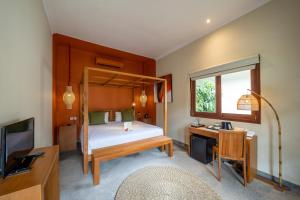una camera con letto, scrivania e TV di Rouge - Villas Ubud ad Ubud