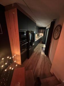 a kitchen with black appliances and a clock on the wall at Aux Secrets De Lora, Chambre de charme VIP in Verviers