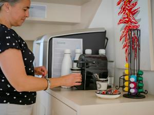a woman standing in front of a coffee maker at Maison d'hôte Iparra- Pays Basque in Arcangues