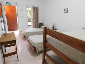 una camera da letto con due letti, un tavolo e una finestra di Hostería Teuly a Puerto Madryn