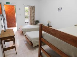 1 dormitorio con 2 camas, mesa y ventana en Hostería Teuly en Puerto Madryn