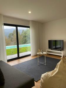 a living room with a tv and a large window at Ri&Vale Alojamentos in Vieira do Minho