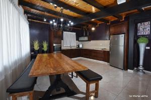 a kitchen with a wooden table and a refrigerator at Villa Troya in Safed
