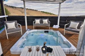 a hot tub on a deck with two chairs and a table at Villa Troya in Safed