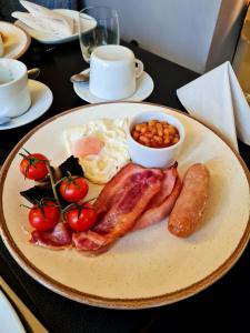 un plato de desayuno con huevos beicon tomates y judías en Furzeleigh Mill, en Buckfastleigh