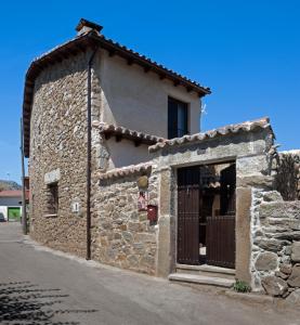 a stone building with a door on a street at Casa Rural El Caldero in Sorihuela