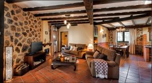 a living room with couches and a tv and a table at Casa Rural El Caldero in Sorihuela