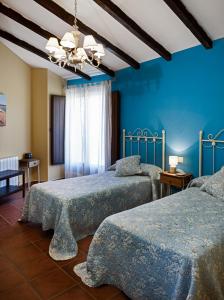sypialnia z 2 łóżkami i niebieskimi ścianami w obiekcie Casa Rural El Caldero Sierra de Béjar w mieście Sorihuela